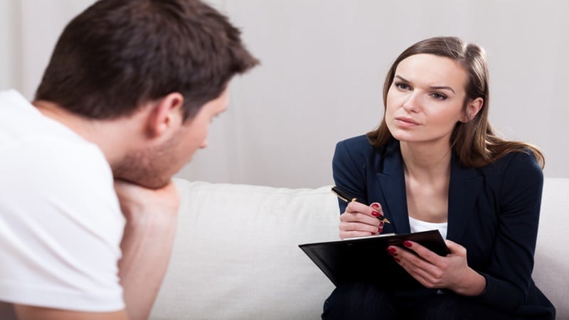 Woman psychologist taking notes on male patient